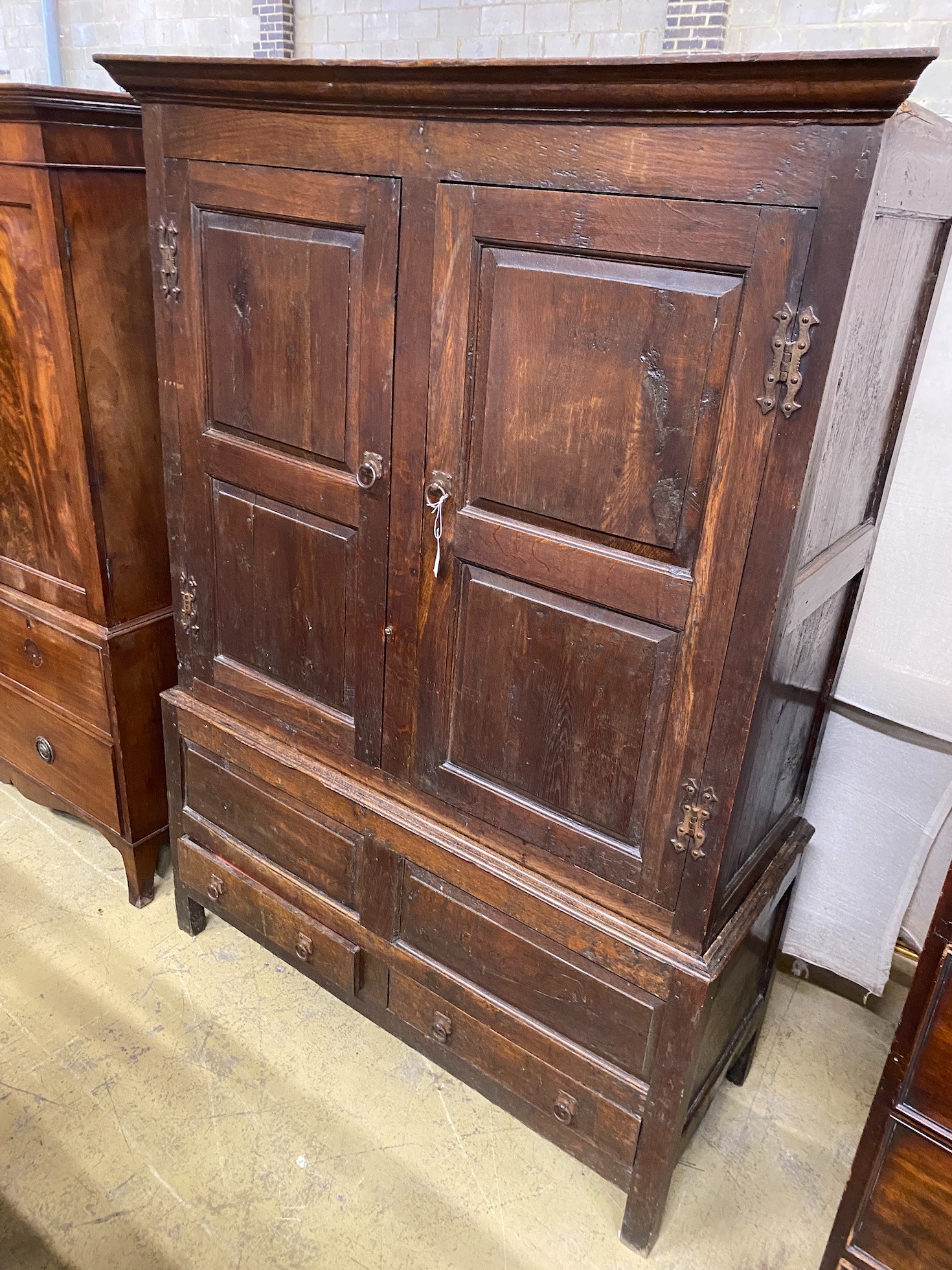 A mid 18th century oak press cupboard with two panelled doors and two drawers